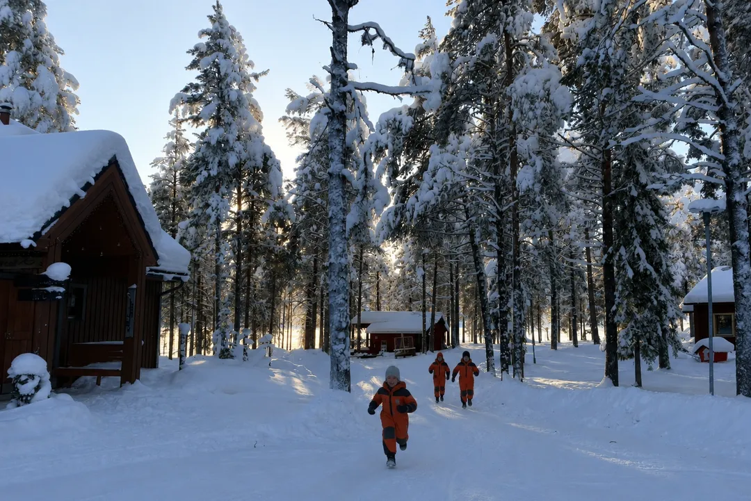 Child running between snowy cabins at Torassieppi resort